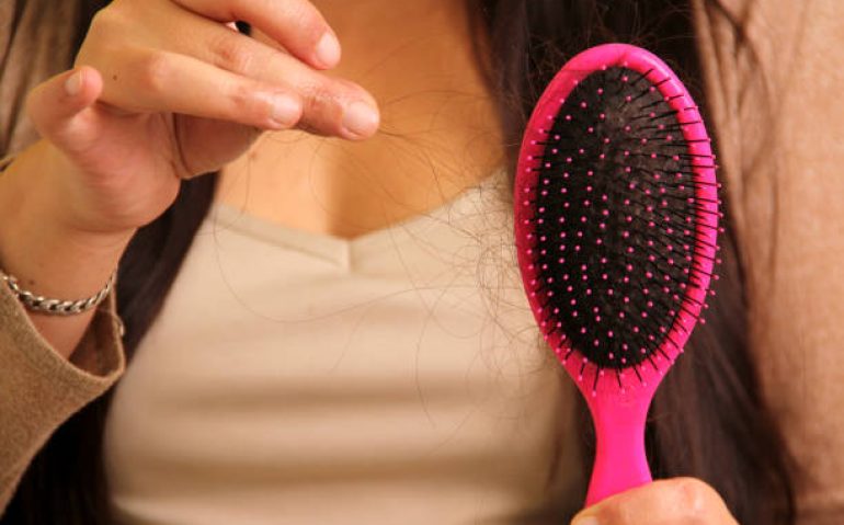 Latin adult woman with very long straight hair suffers from hair loss looking at the brush how many hairs fall out in one brush