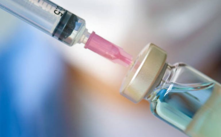 Doctor's hand holds a syringe and a blue vaccine bottle at the hospital. Health and medical concepts
