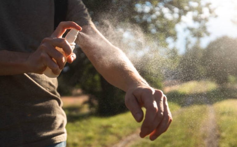 Prevention against mosquito bite during sunny summer day. Man is applying insect repellent on his hand.