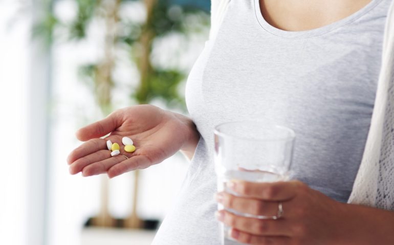 Unrecognizable young mother taking medicine